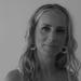 Lucy Olsen, has long shoulder length hair an smiling at the camera in a black and white photo.