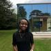Diana mwala has shoulder length black braids, wearing a black dress smiling at the camera directly.
