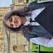 Shrutika is standing in front of the Radcliffe Camera in Oxford. She is wearing subfusc clothing, including a white shirt, black gown, black tie and black cap.