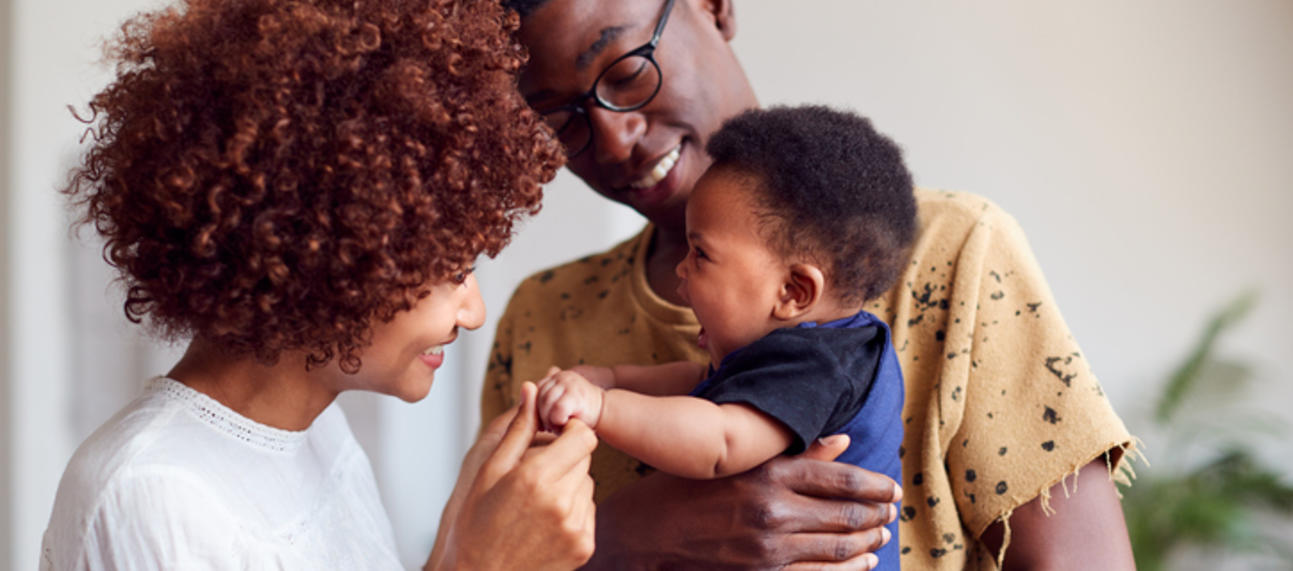 Two parents holding and playing with their young baby. 