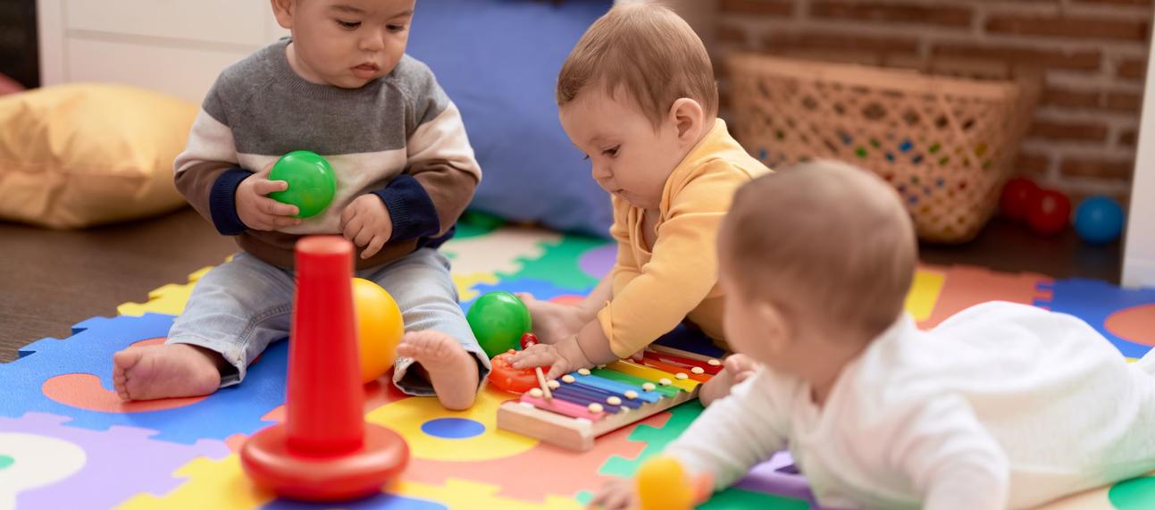 Three babies playing on a colourful floor matt. Photo credit: stock.adobe.com / Krakenimages.com