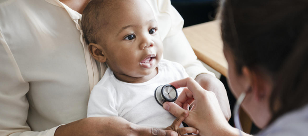 A doctor pressing a stethoscope to a baby's chest