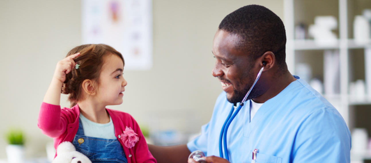A young girl interacting with a healthcare worker, who is smiling and holding a stethoscope