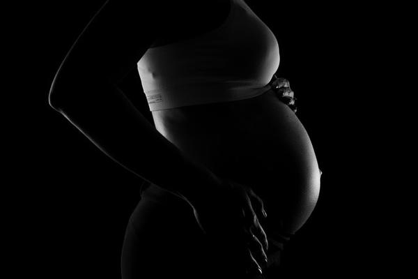 Black and white side profile silhouette of a pregnant woman