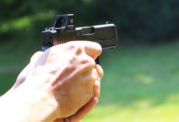 A man's hand holds out a handheld shotgun, aiming at nothing