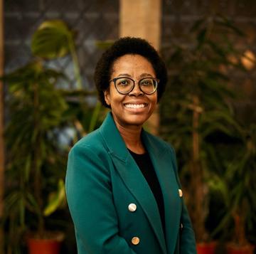 Zamakhanya Makhanya has afro hair, with black rimmed glasses, weating a green jacket smiling at the camera.