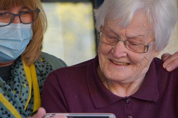 Careworker in a facemask helps elderly woman