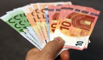Basic income a hand holding a fan of Euros