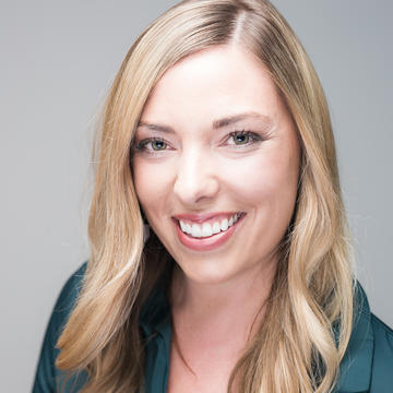 Kristen de Graaf has blonde shoulder-length hair and is wearing a dark jacket, smiling at the camera.