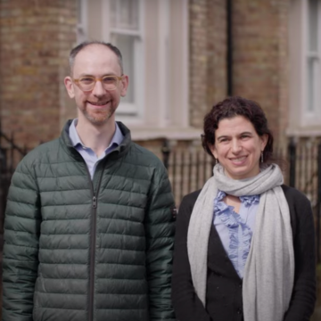   Lucie Cluver and Seth Flaxman are standing in front of a brick building.  