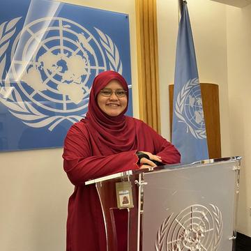 A Muslim woman dressed in a hijab standing at a podium 