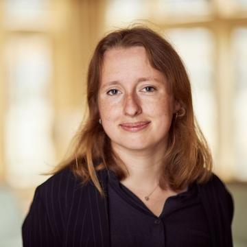 Inga has shoulder length red hair, wearing a black top smiling at the camera.