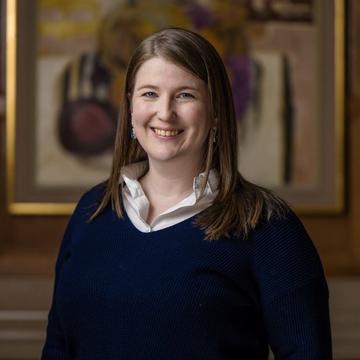 Julia Schaub has shoulder length ginger brown hair, with a dark top smiling at the camera.