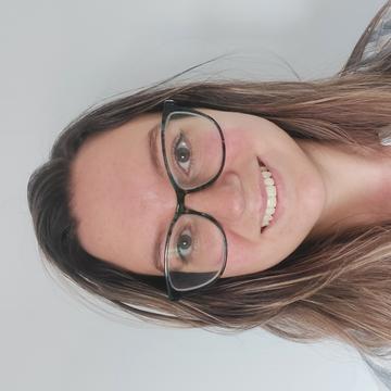 Tamara Lister has shoulder-length hair, wears glasses, and is smiling at the camera.