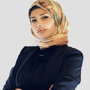 Afnan Attrash-Najjar is wearing a head covering with a dark blue jacket looking at the camera.