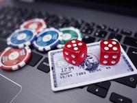 An image of dice, poker chips, and a credit card on a laptop keyboard.