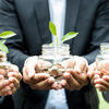 Getty Images - Three people holding a pot each with coin growing a plant.