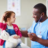 A young girl interacting with a healthcare worker, who is smiling and holding a stethoscope