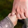Close up of child and parent linked hand in hand