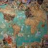 A colourful world map filled with pushpins and international currency