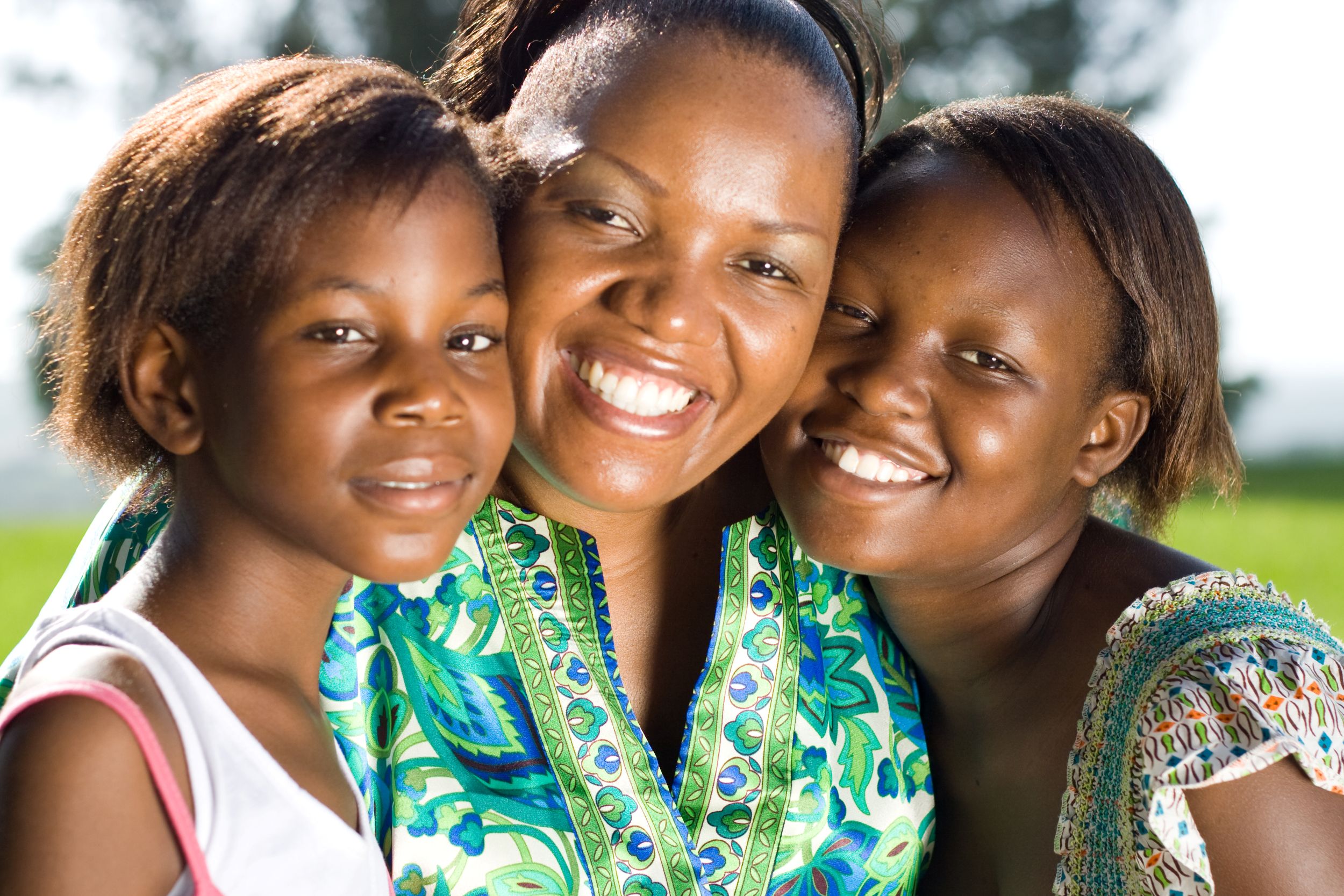 A mother and her two daughters, smiling broadly at the camera