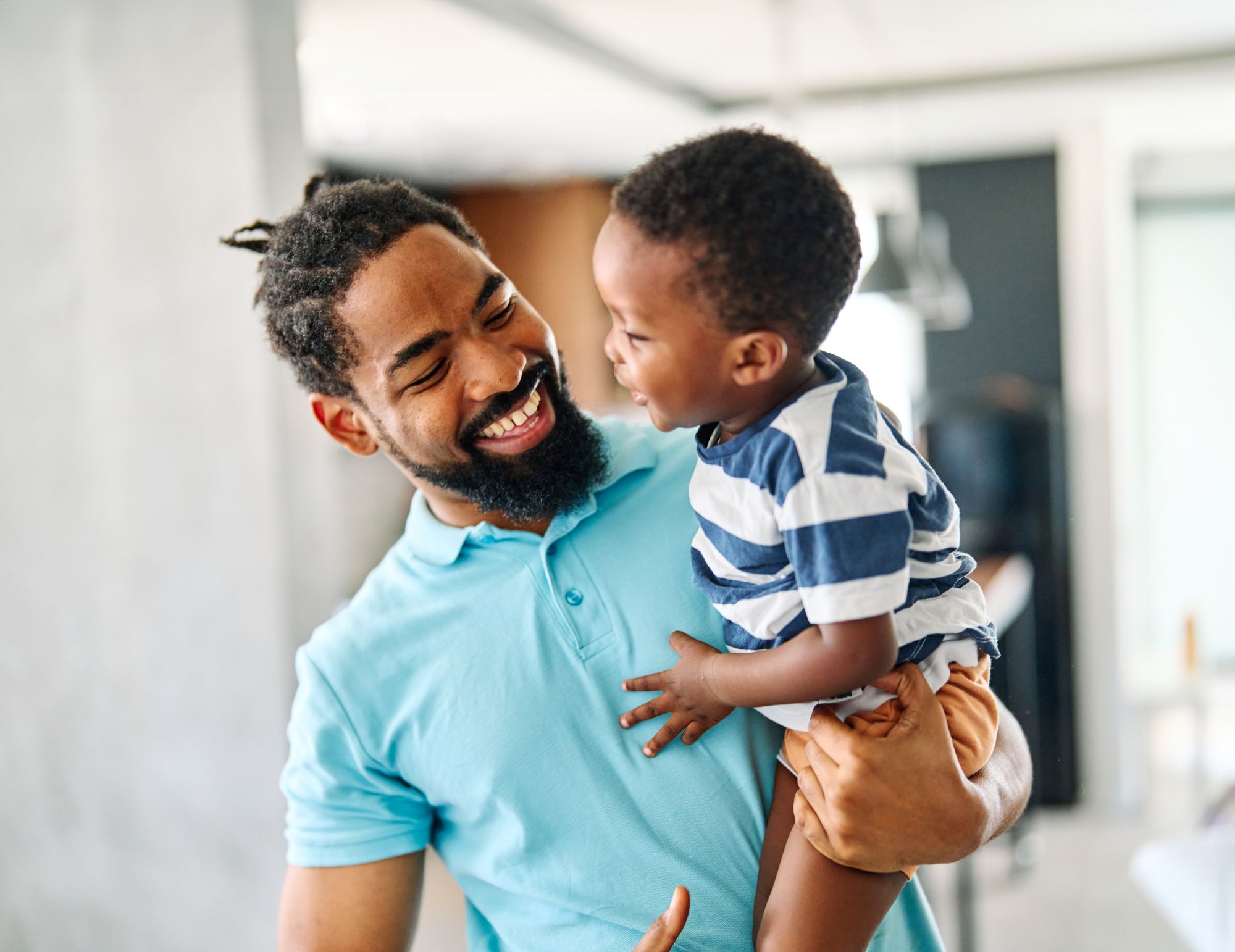 A father holding his young son, laughing together