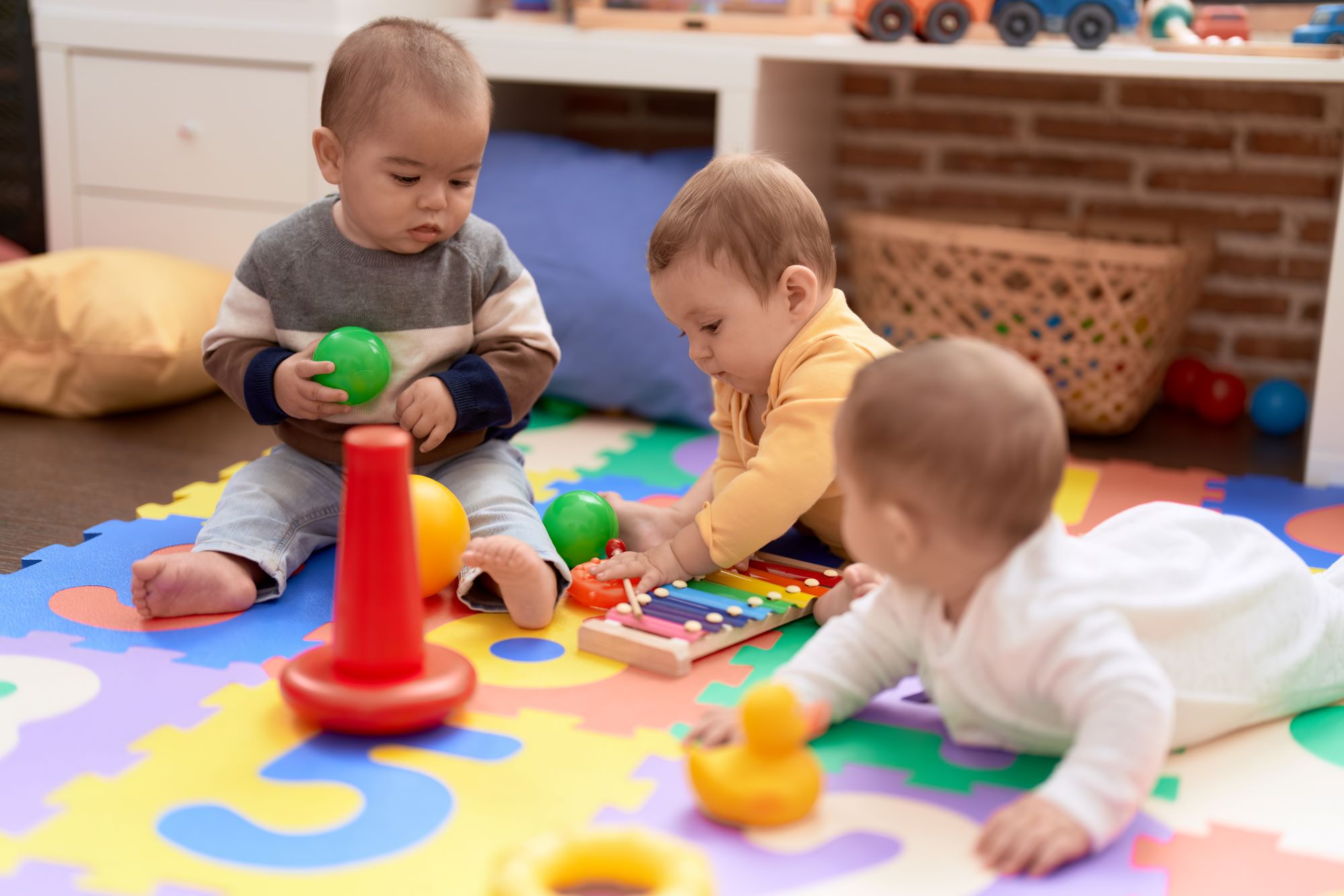 Three babies playing on a colourful floor matt. Photo credit: stock.adobe.com / Krakenimages.com