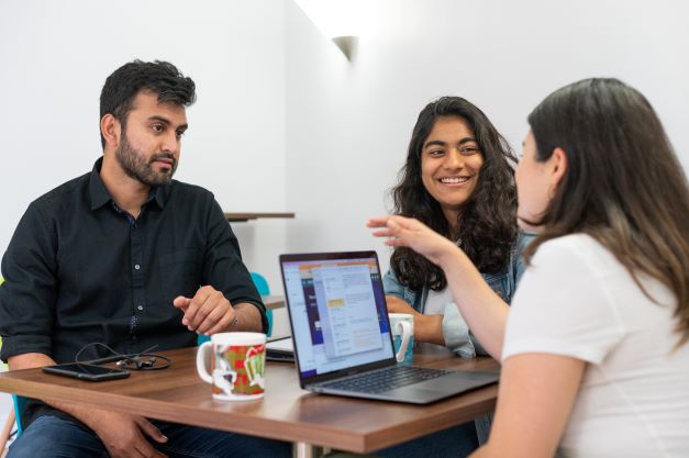 DSPI students chatting around a laptop at Barnett House