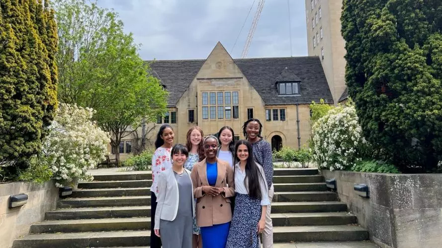 A group of students standing on some steps in front of an Oxford college building