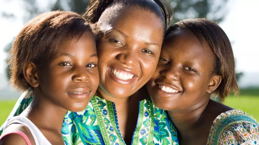 A mother and her two daughters, smiling broadly at the camera