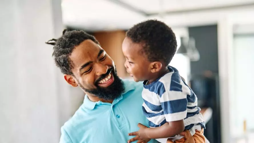 A father holding his young son, laughing together