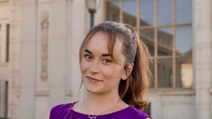 Christina Mueller wears a purple dress. She stands outside. 