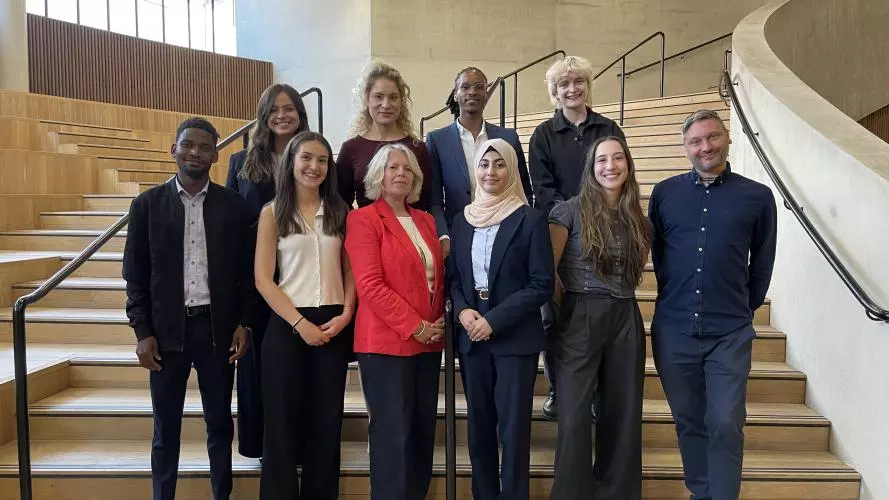 Two rows of smiling people standing on a sweeping stairway - 4 on the back row, six on the front row