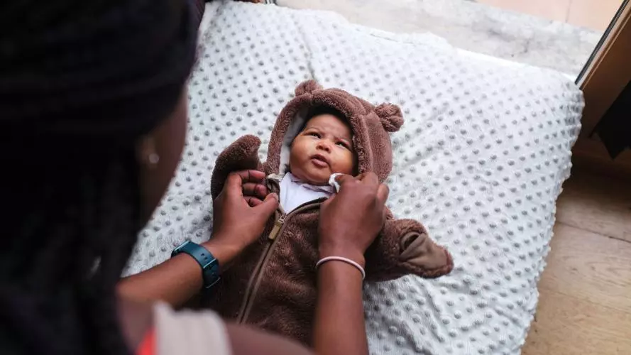 Mother putting pyjamas on newborn. 
