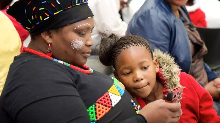 A person and a child looking at a mobile phone