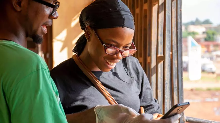 Two community health workers discuss the results shown on a handheld device.