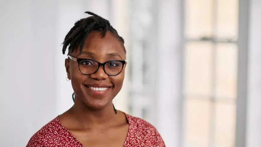 Sopuruchukwu has short black hair and is wearing glasses. She's wearing a red top with small white and pink patterns.  