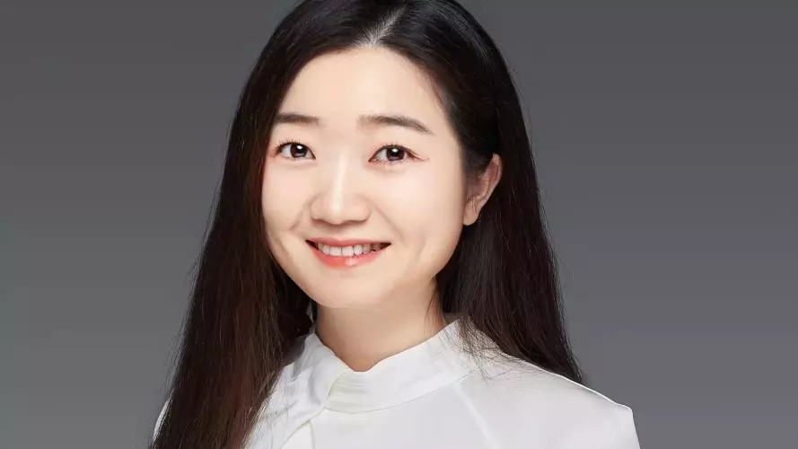 Zuyi Fang is smiling at the camera, she has long hair past her shoulders and is wearing a white top.