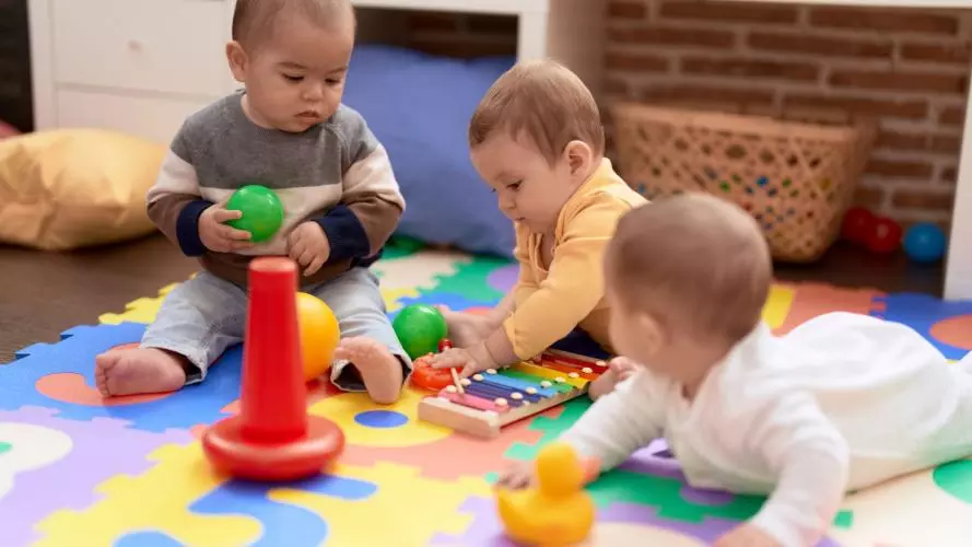 Three babies playing on a colourful floor matt. Photo credit: stock.adobe.com / Krakenimages.com