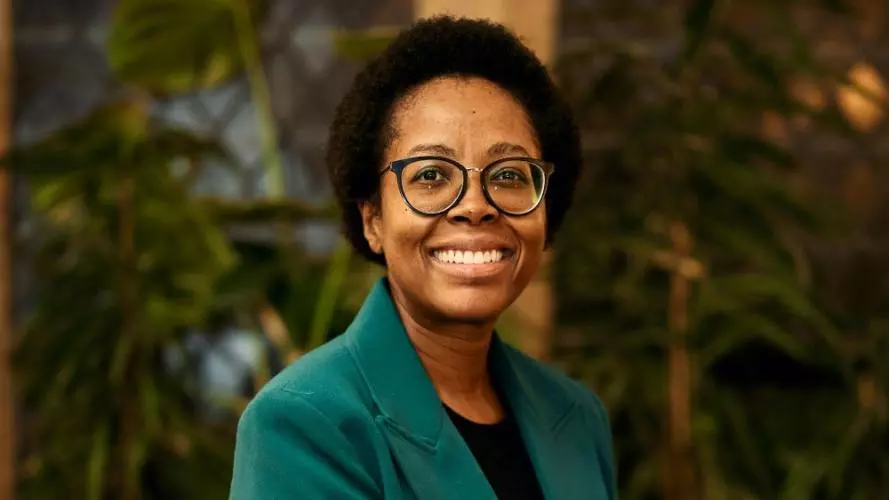 Zamakhanya Makhanya has afro hair, with black rimmed glasses, weating a green jacket smiling at the camera.