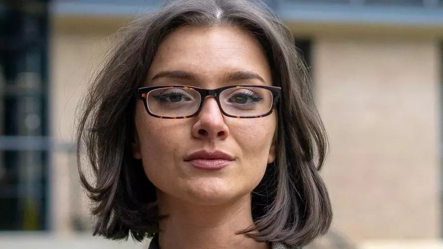 Aliyah Hurt has bobbed brown hair and is wearing a blazer and glasses.