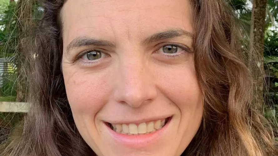 Ellen has long brown wavy hair and is smiling at the camera. 