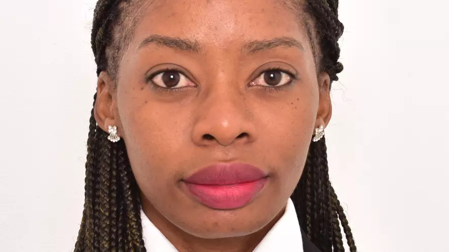 Looking directly at the camera, Katongo is wearing a white top, black jacket and shoulder-length black braids.