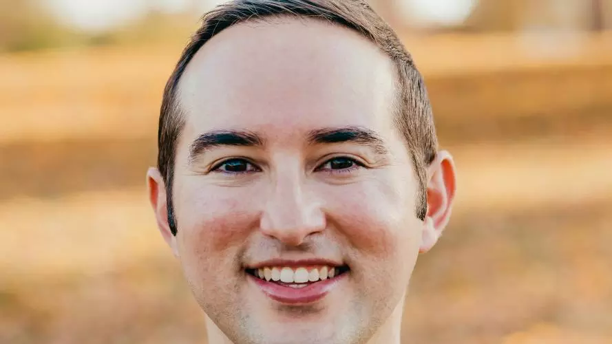 Paul Penahas short brown hair, wearing a green top smiling at the camera.