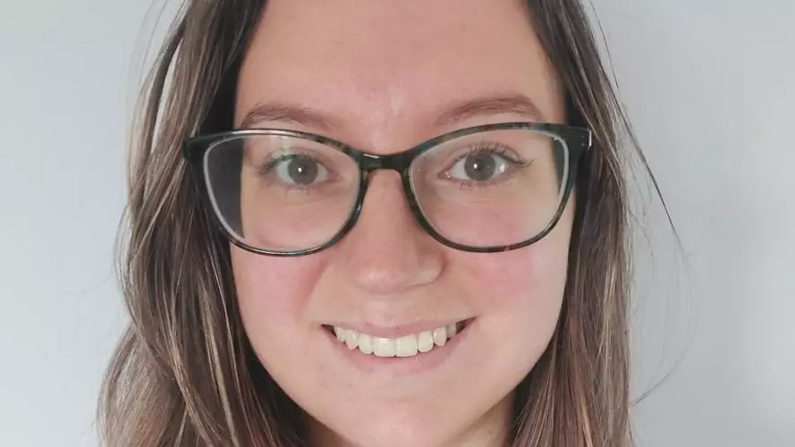Tamara has long hair and is wearing dark glasses, smiling at the camera. 