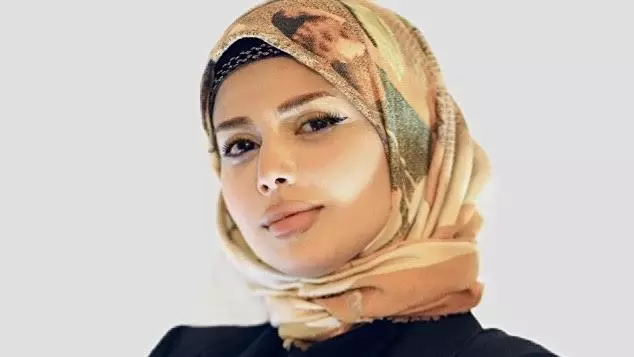 Afnan Attrash-Najjar is wearing a head covering with a dark blue jacket looking at the camera.