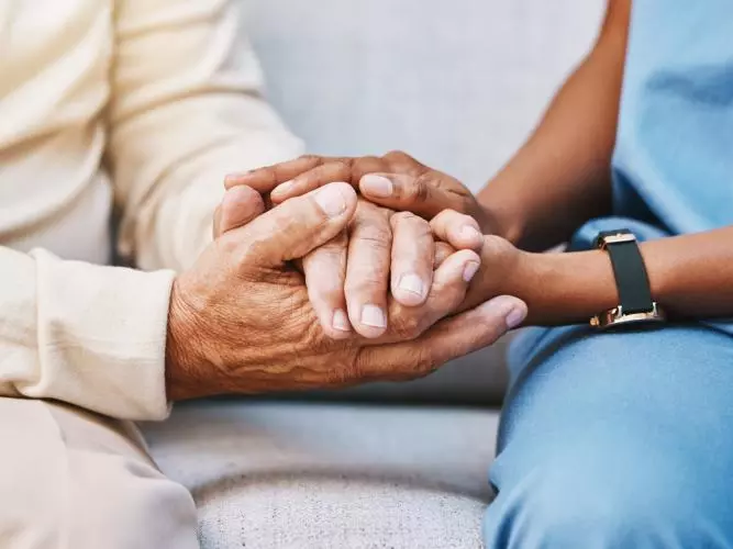A close-up image of a nurse and a patient holding hands. Credit: Getty - PeopleImages 1473155461