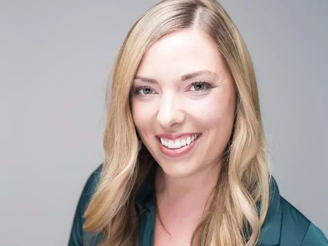 Kristen de Graaf has blonde shoulder-length hair and is wearing a dark jacket, smiling at the camera.