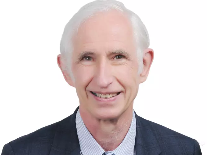 Robert  has grey hair and is smiling at the camera. He's wearing a shirt, tie and suit jacket 