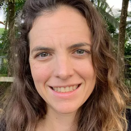 Ellen has long brown wavy hair and wearing a black top. She is smiling at the camera. 